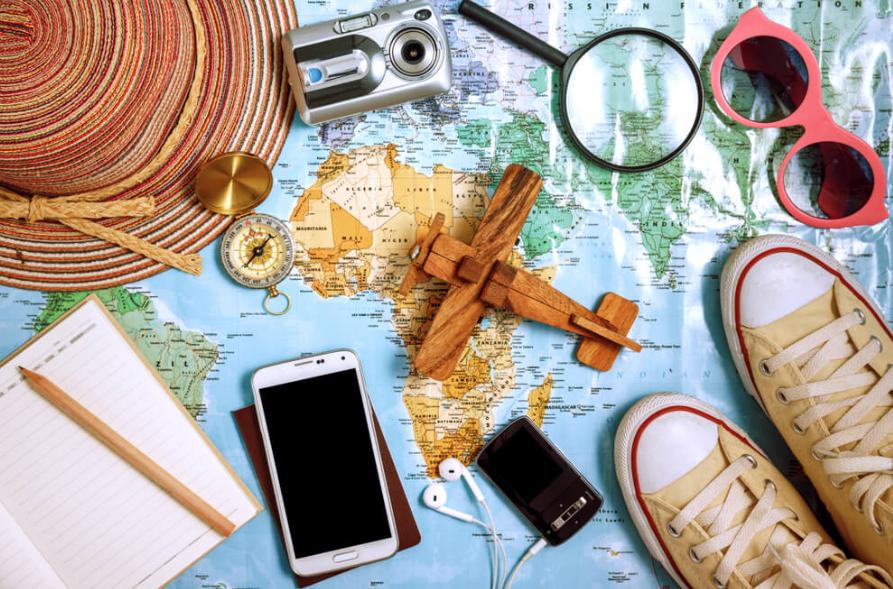 Mapa de viaje con cámara, brújula, sombrero, gafas, zapatillas y dispositivos móviles